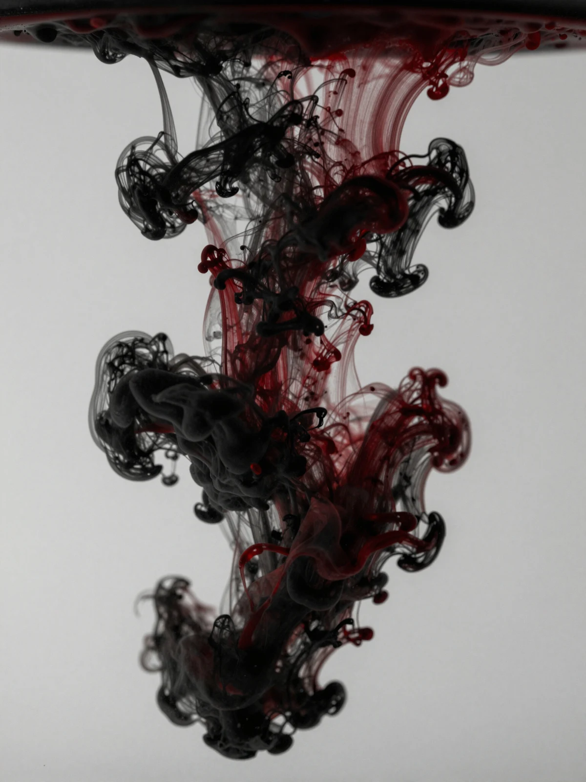 Inchiostro rosso e nero che si diffonde nell’acqua
